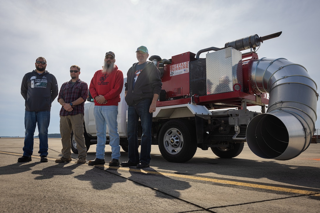 Sean Wales, a foreign object debris attendant, left; Scott Nickson, the FOD Supervisor; Timothy Fraunfelder, a FOD attendant; and Rudolf Zanaska, a FOD attendant; stand in front of a FOD blower at Marine Corps Air Station Cherry Point, North Carolina, Feb. 25, 2025.