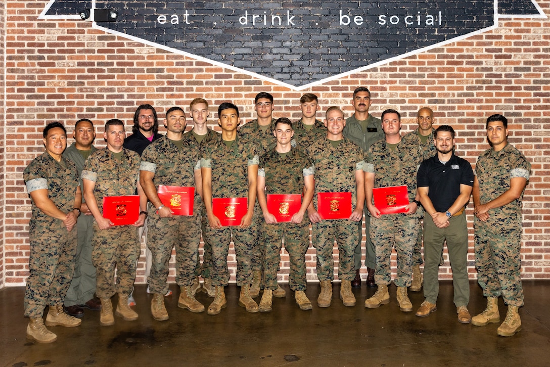 Graduates of the MQ-9 Reaper aircraft Ground Control System technician course stand for a photo with Center for Naval Aviation Technical Training Unit Cherry Point leadership and instructors, during a graduation ceremony at the Cherry Point Public House, Marine Corps Air Station Cherry Point, North Carolina, June 18, 2025.