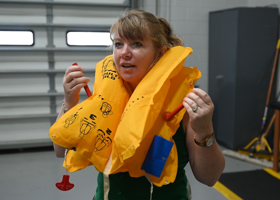 Stephanie Hamby, a 17th Training Wing honorary commander, tries on a personal flotation device while at Dyess Air Force Base, Texas Aug. 6, 2025. The Goodfellow Honorary Commander Program introduces civic leaders to the missions of the U.S. Air Force, and the U.S. Department of Defense.(U.S. Air Force photo by Staff Sgt Nathan Call)
