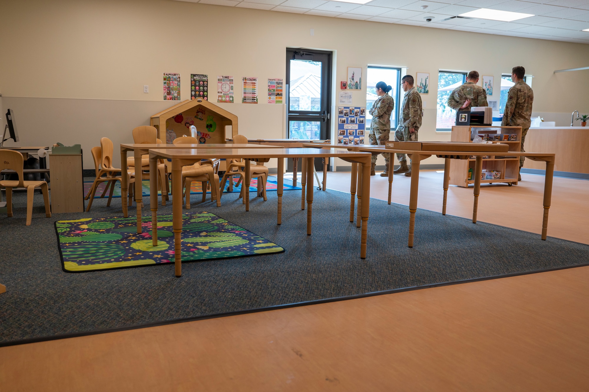 A picture of the newly renovated child development center with fou people standing next to the window.