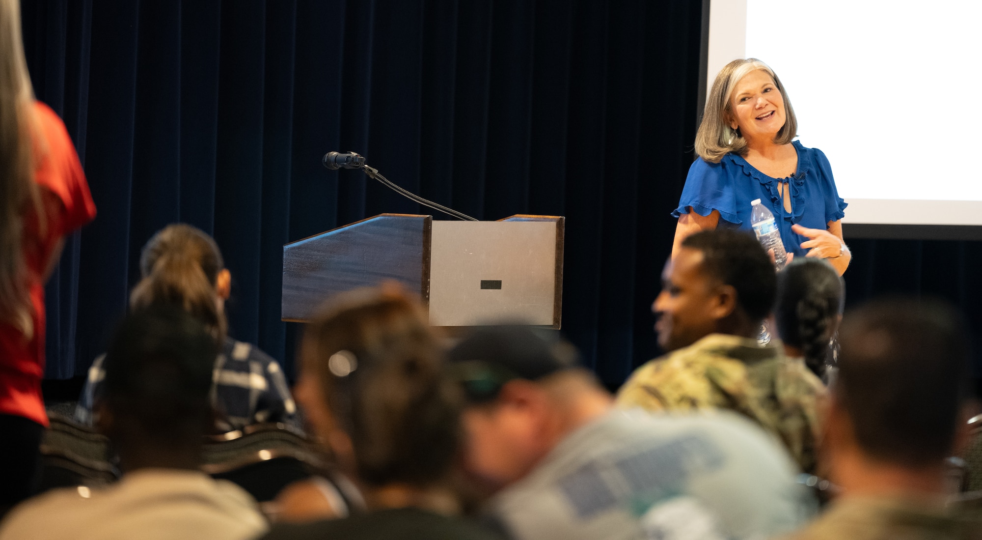 Ms. Christy shares her story while walking around the front of the room at the event.