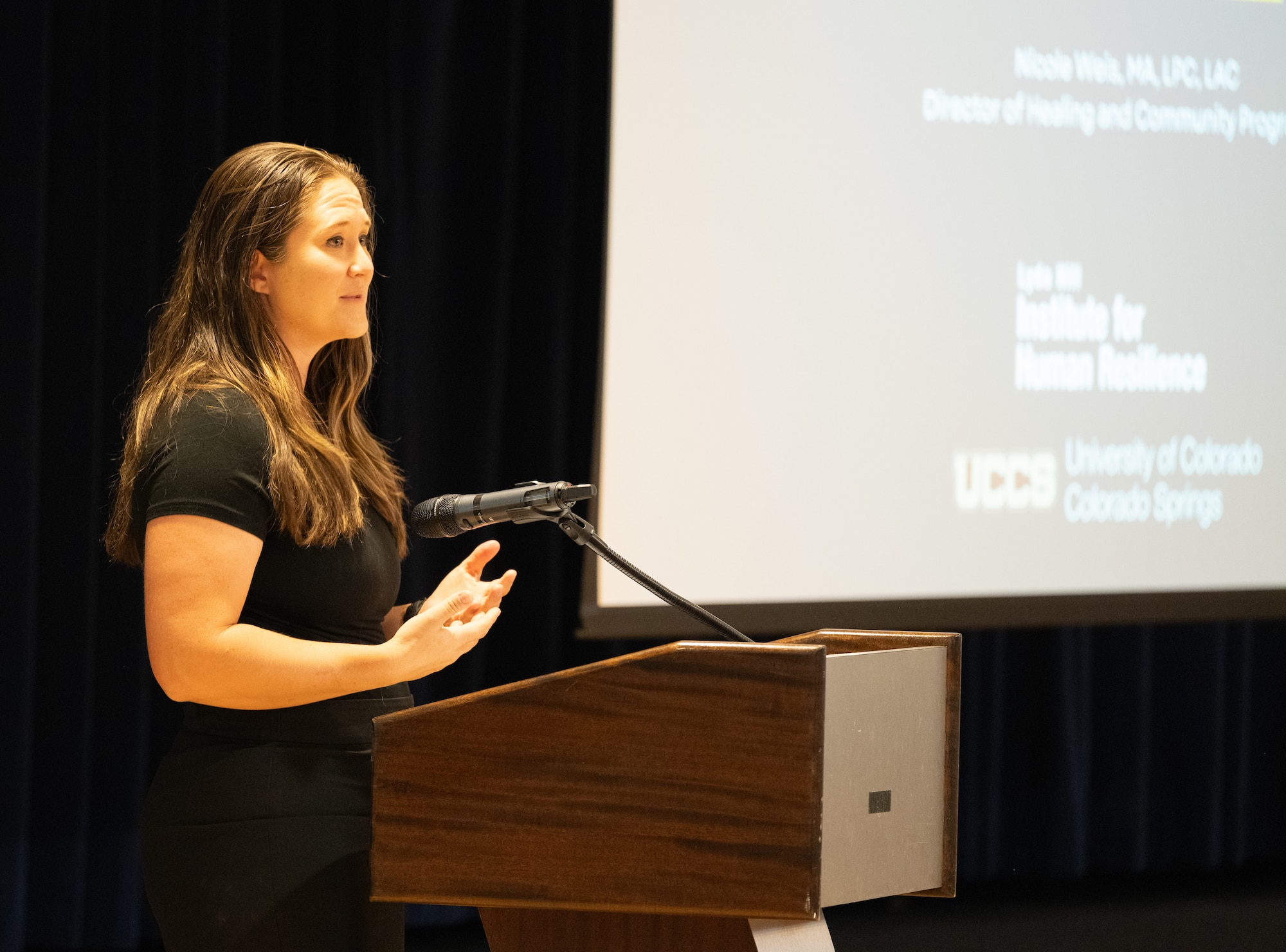 Mr. Weis addresses her audience from behind a podium during the event.