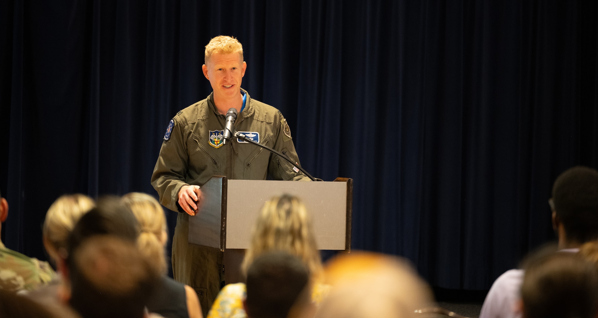 Col. Elliot stands behind a podium addressing the audience at the event.