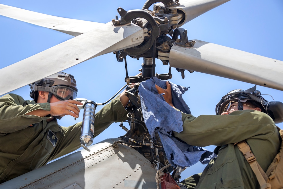 U.S. Marine Corps Lance Cpl. Jordan Flores, left, a flight line mechanic with Marine Light Attack Helicopter Squadron (HMLA) 367, Marine Aircraft Group 39, 3rd Marine Aircraft Wing, and Lance Cpl. Gavin Thein, a UH-1 helicopter crew chief with HMLA-369, MAG-39,  service a UH-1Y Venom assigned to HMLA-369during  Service Level Training Exercise 4-25 at Marine Corps Air-Ground Combat Center,  Twentynine Palms, California, Aug. 10, 2025. SLTE 4-25 is designed to be a challenging, realistic training environment that produces combat-ready forces capable of operating as an integrated Marine Air Ground Task Force across all domains of military operations. Lance Cpl.  Flores is a native of Nevada. Lance Cpl. Thein is a native to California. (U.S. Marine Corps photo by Lance Cpl. Seferino Gamez)