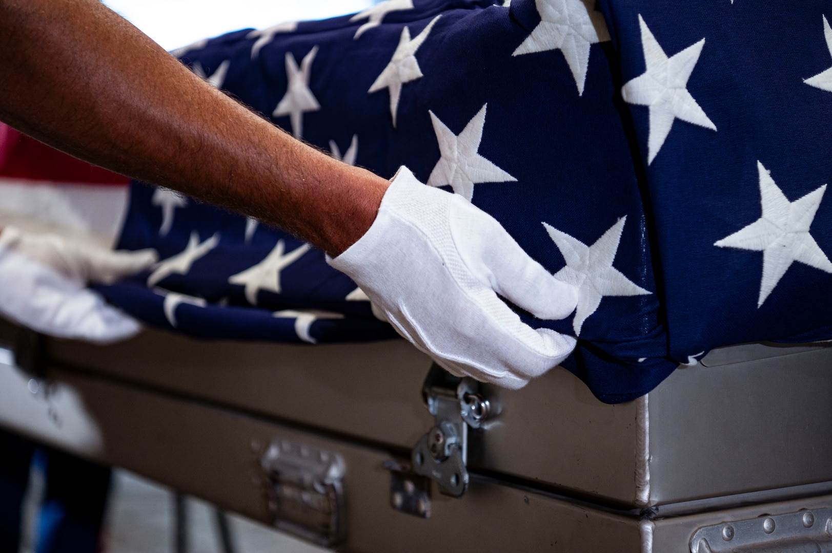 U.S. Navy Chief Petty Officer Alexander Greenspan, an explosive ordnance disposal technician assigned to the Defense POW/MIA Accounting Agency, secures the American flag to a casket holding potential remains during a repatriation ceremony in Da Nang Province, Vietnam, July 25, 2025.