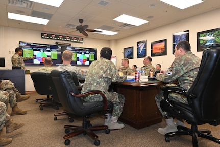 Leadership sits at table to discuss cyber partnership.
