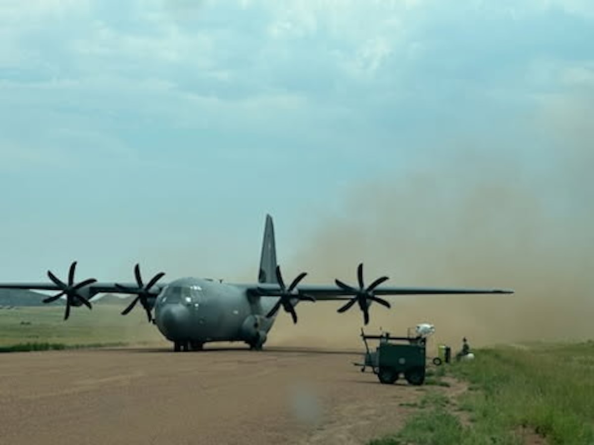 A military aircraft sits on a dirt strip.