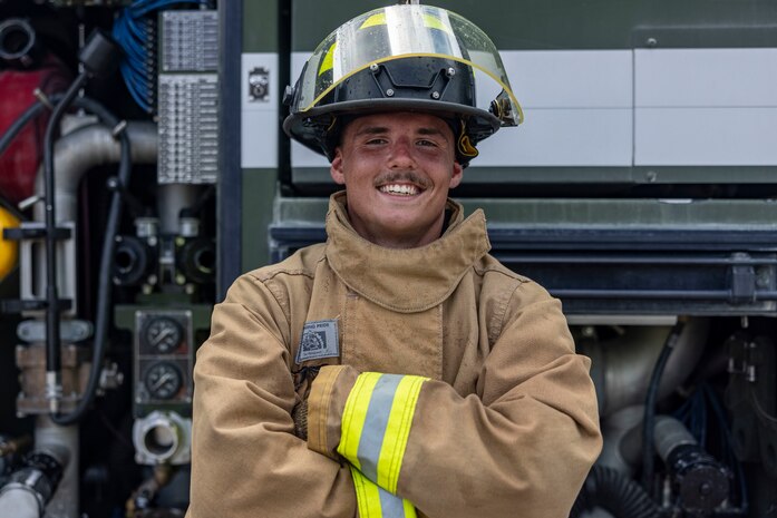 U.S. Marine Corps Cpl. Aaron Smith, an expeditionary firefighting and rescue specialist with Aircraft, Rescue, and Firefighting, Marine Corps Air Station Cherry Point, stands beside a P-19R ARFF truck at MCAS Cherry Point, North Carolina, July 11, 2025. Marines with ARFF conducted pit drills to practice advancing toward a simulated fuel fire, pushing it into a single location and suppressing the fire, with goals of sharpening communication skills and building teamwork and trust on the firegrounds. (U.S. Marine Corps photo by Sgt. Samantha Rodriguez)