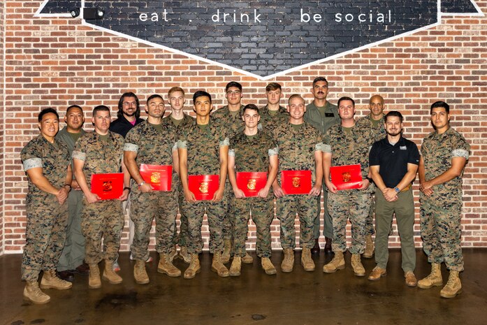 Graduates of the MQ-9 Reaper aircraft Ground Control System technician course stand for a photo with Center for Naval Aviation Technical Training Unit Cherry Point leadership and instructors, during a graduation ceremony at the Cherry Point Public House, Marine Corps Air Station Cherry Point, North Carolina, June 18, 2025. The graduation of the first class of MQ-9 Reaper aircraft GCS technicians established the military occupational specialty and marked a step towards the implementation of Force Design 2030 - the official doctrine published by the Marine Corps to outline the evolution of the organization's warfighting in the 21st century. (U.S. Marine Corps photo by Lance Cpl. Lauralle Gavilanes)