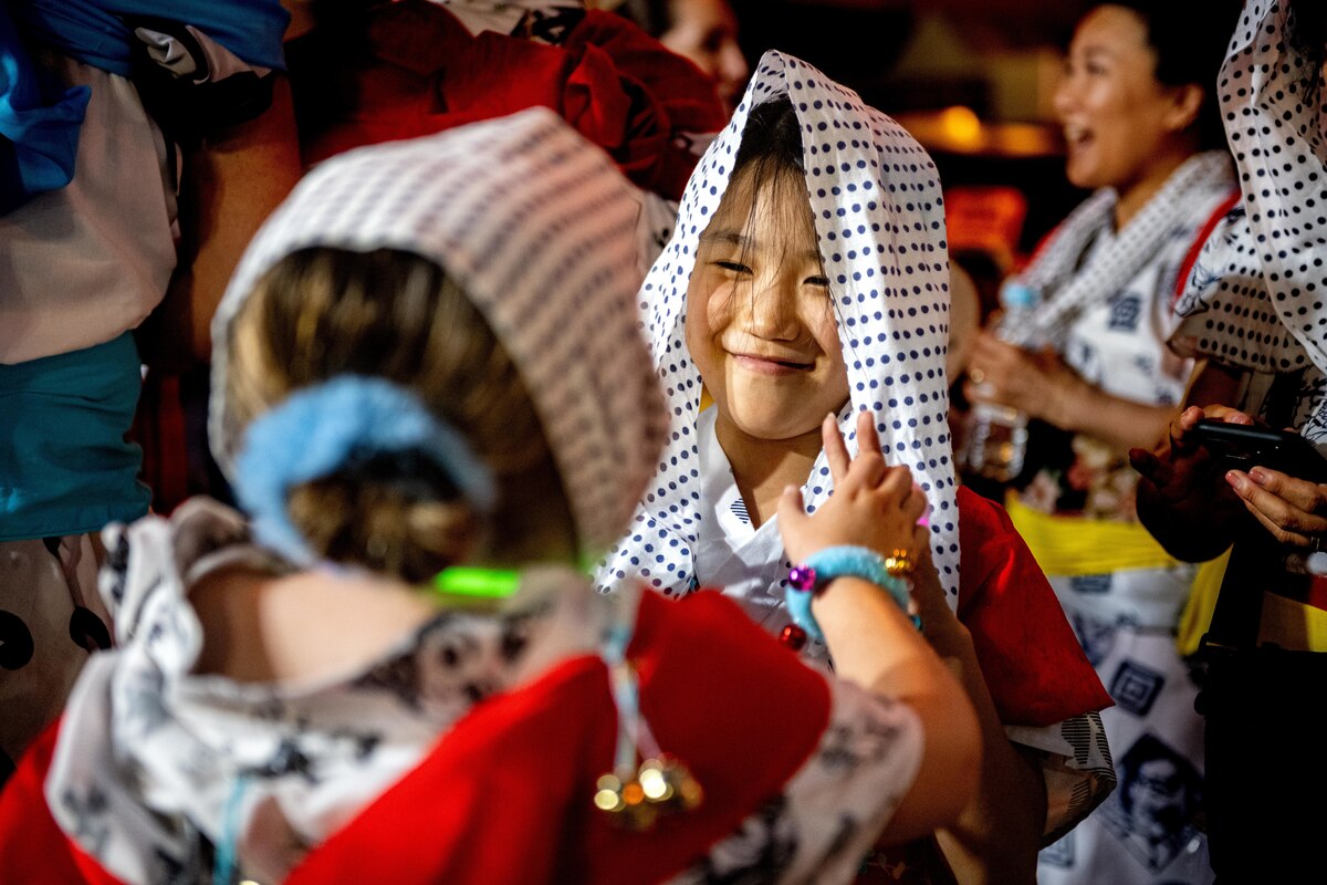 An American Nebuta festival participant ties a head covering around a Japanese participant during the annual Nebuta Festival at Aomori City.