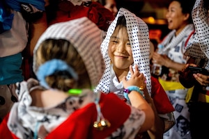 An American Nebuta festival participant ties a head covering around a Japanese participant during the annual Nebuta Festival at Aomori City.