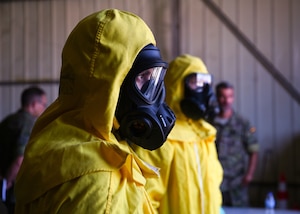 spanish and u.s. armed forces learning and practicing cbrne protocols, someone classroom, some in yellow hazmat suits