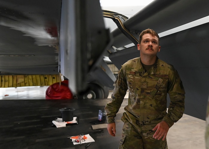 A man in military uniform looks at a plane wing.