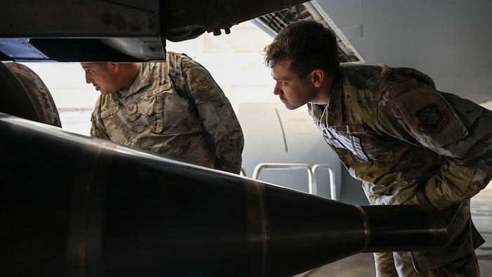 Two men examine a large engine.