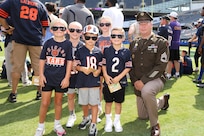 Sgt. 1st Class Charles Almburg, left, G-3 Operations Non-commissioned Officer, 85th U.S. Army Reserve Support Command, pauses for a photo with a group of young Chicago Bears fans just before the start of the Bears pre-season game with the Miami Dolphins at Soldier Field, August 10, 2025.
