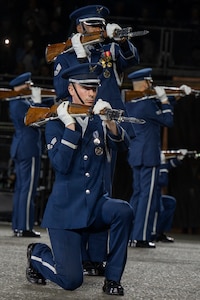 U.S. Air Force Senior Airman Crìsdean James Langan, kneeling center, ceremonial guardsman with the U.S. Air Force Honor Guard Drill Team, conducts a kneeling-bone-crusher drill movement during a performance of the 75th Royal Edinburgh Military Tattoo in Edinburgh, Scotland, Aug. 1, 2025. Military bands and drill teams from the U.S., United Kingdom, Switzerland, Canada, Germany, Poland, and Ukraine performed during the 24-day event. (U.S. Air Force photo by Hayden Hallman)