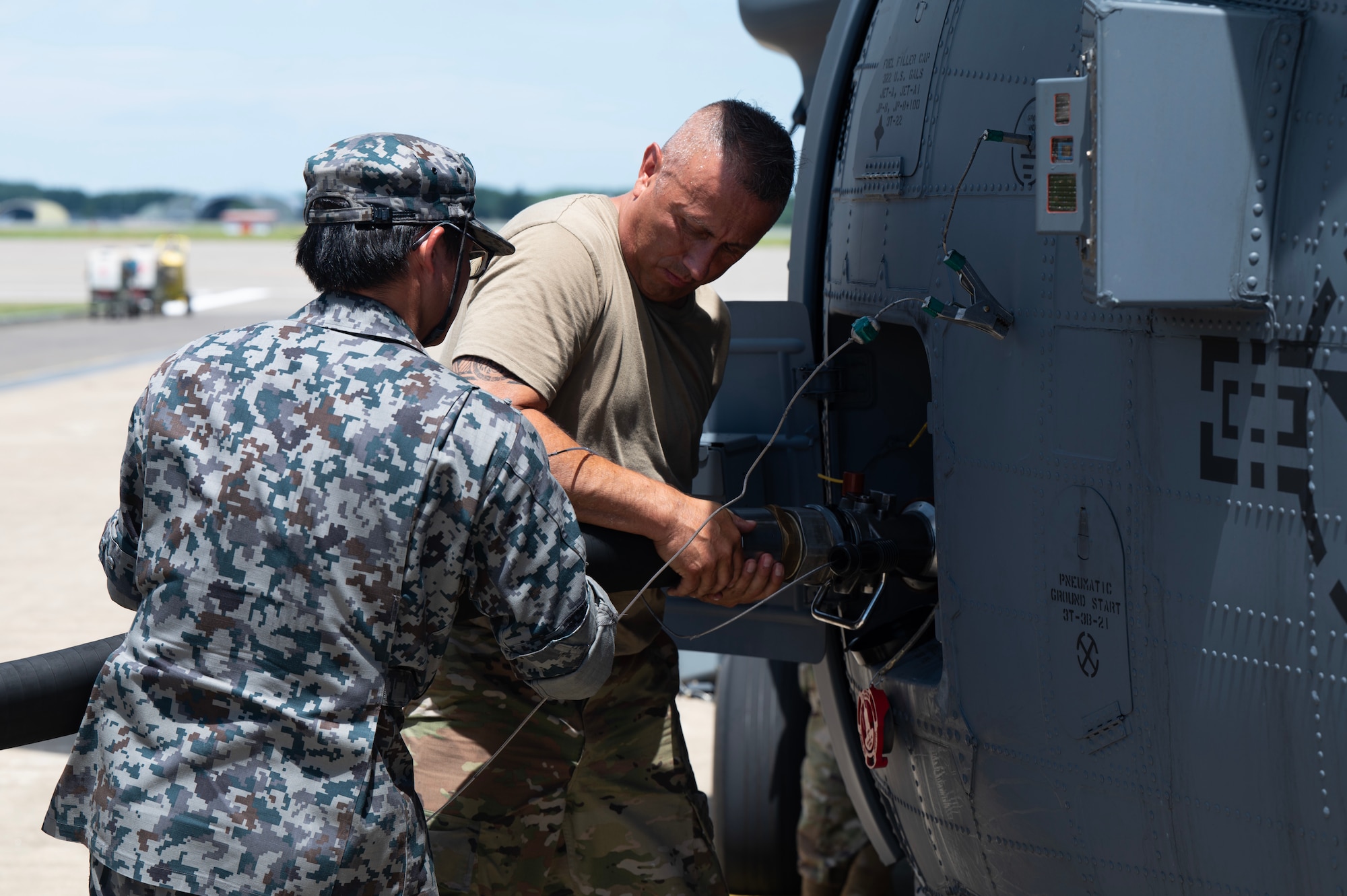 U.S. Air Force Staff Sgt. John Marin, an HH-60W crew chief with the 106th Rescue Wing, works with a Japan Air Self-Defense Force refueling technician to refuel an HH-60W Jolly Green II search and rescue helicopter during exercise Resolute Force Pacific (REFORPAC) 2025 at Misawa Air Base, Japan, July 22, 2025.