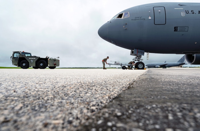 U.S. Air Force Airmen assigned to the 22nd Aircraft Maintenance Squadron, and the 64th Air Refueling Squadron, prepare to tow a KC-46 Pegasus aircraft to a new parking spot on the flight line during the U.S. Air Force’s 2025 Department-Level Exercise series at Andersen Air Force Base, Guam, July 24, 2025. The DLE strengthens and demonstrates the U.S. Air Force’s ability to reach theater at speed and scale, sustain operations, and rapidly pivot to any theater of operation at a moment’s notice while maintaining the strategic initiative. The DLE series encompasses all branches of the Department of Defense, along with Allies and partners, employing more than 400 joint and coalition aircraft and more than 12,000 personnel across more than 50 locations across 3,000 miles. (U.S. Air Force photo by Staff Sgt. Tryphena Mayhugh)