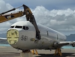 An airplane is cut by large shears on a tarmac.