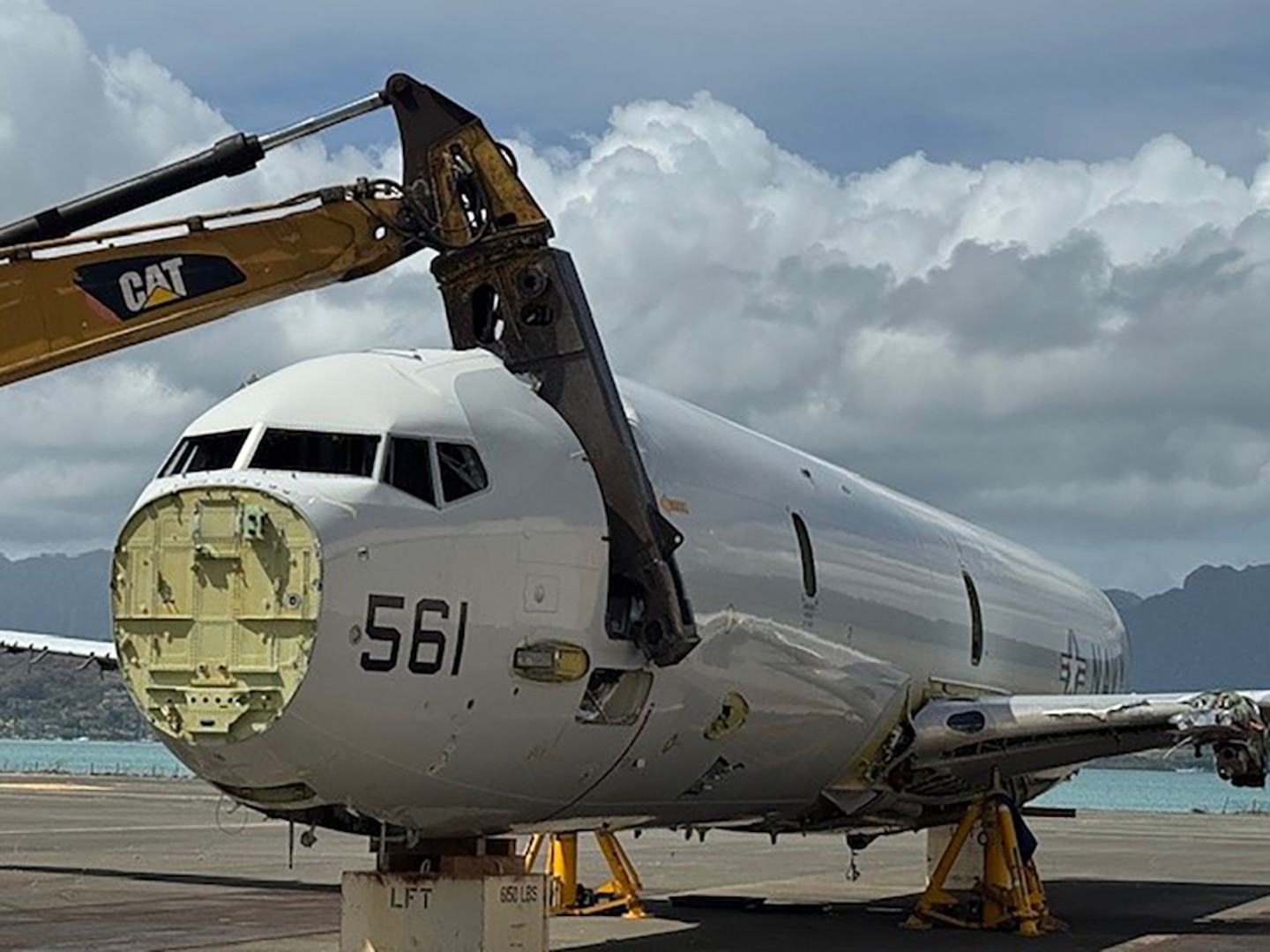 An airplane is cut by large shears on a tarmac.