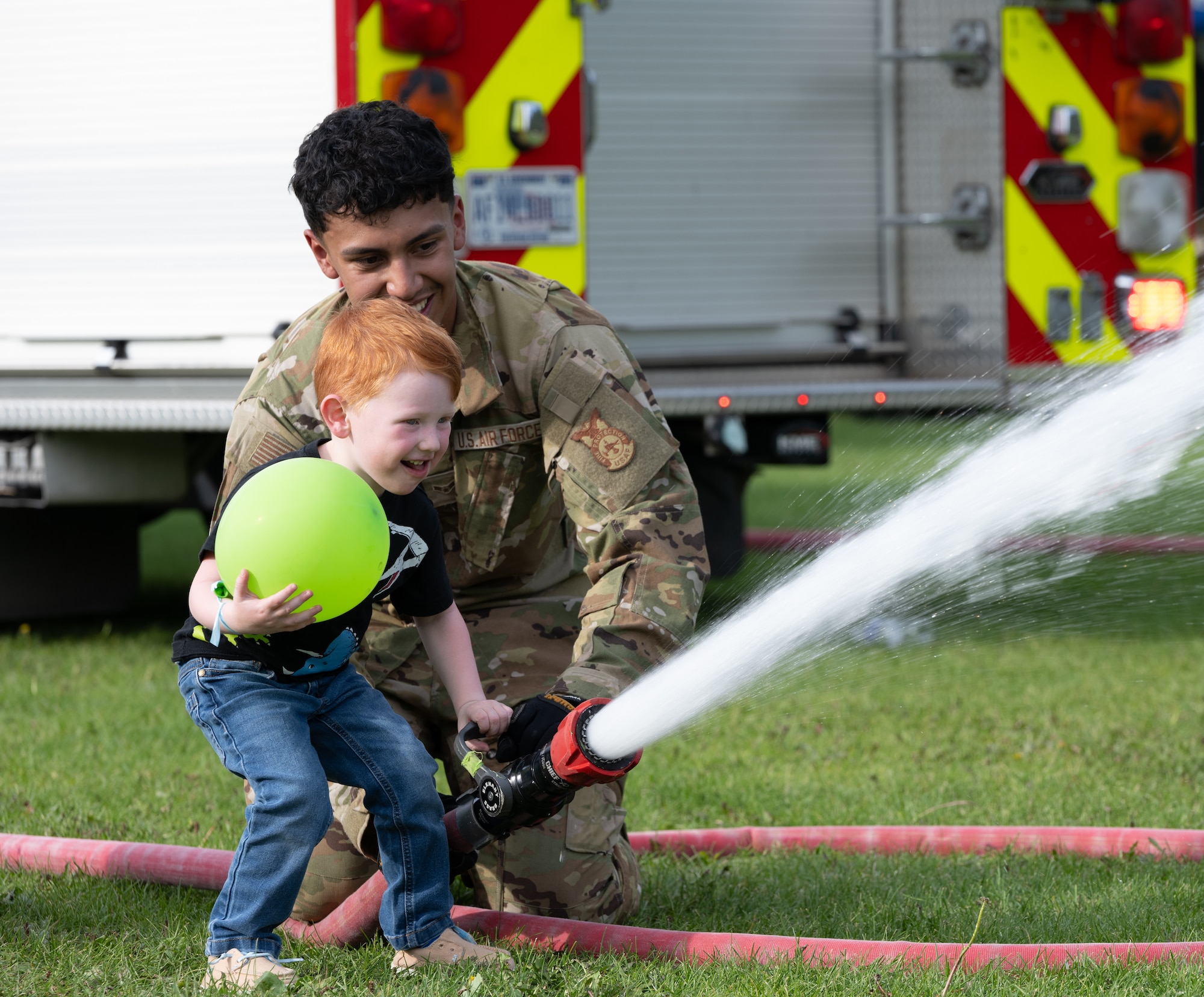 Airman First Class Estrado shows a child how to use the fire truck's hose.