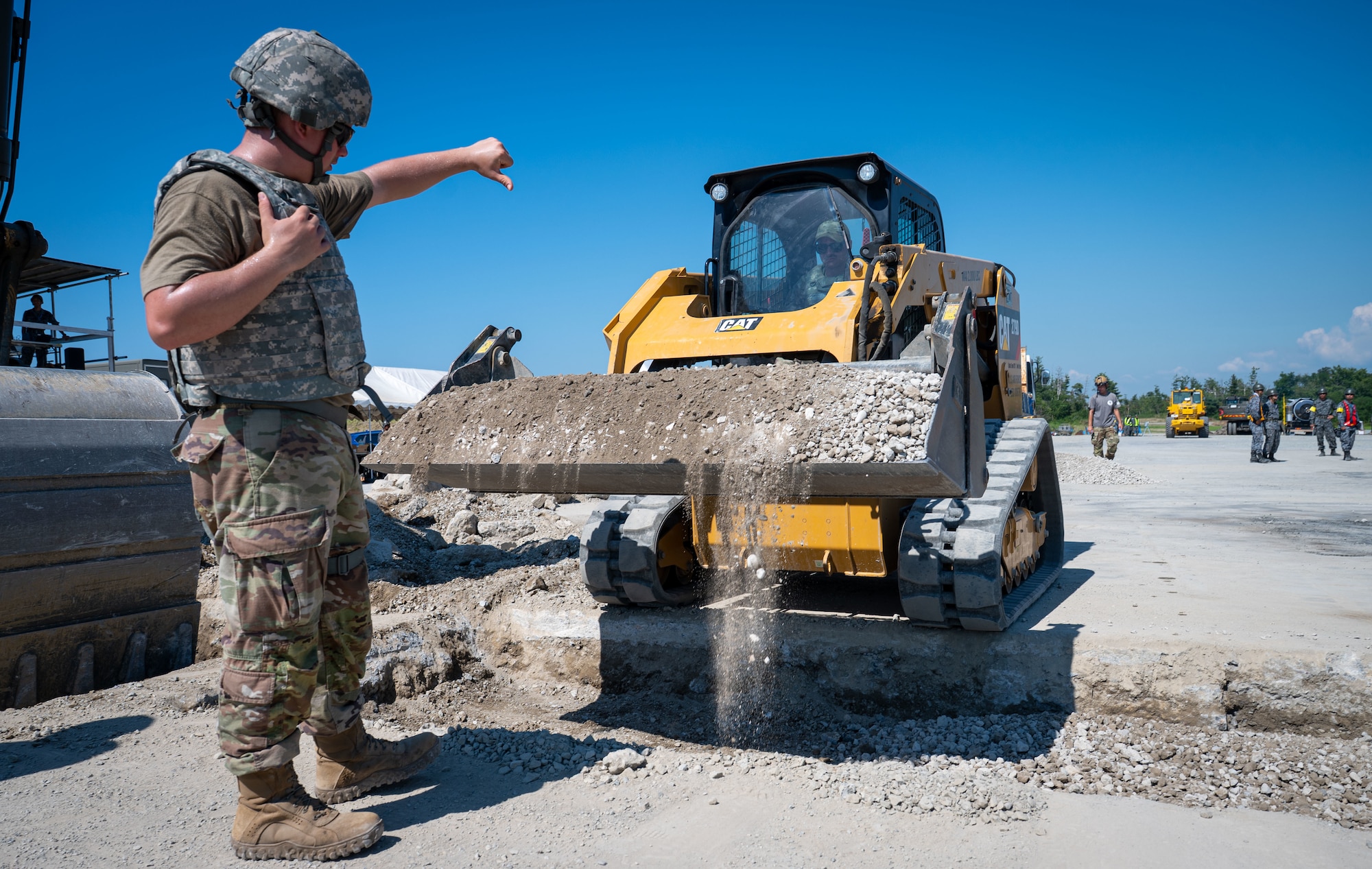 Airman guides a skid-steer loader operator.