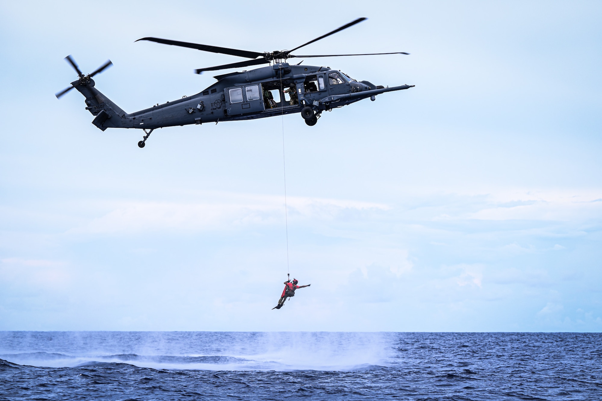 A U.S. Air Force pararescueman from the 563rd Rescue Group hoists down from an HH-60W Jolly Green II helicopter to rescue a simulated downed pilot during exercise Resolute Force Pacific in Saipan, Northern Mariana Islands, July 18, 2025. The HH-60W was designed for mission critical operations to include personnel recovery, humanitarian missions, civilian search and rescue, disaster relief, medical evacuation and non-combatant evacuations. (U.S. Air Force photo by Senior Airman Andrew Garavito)
