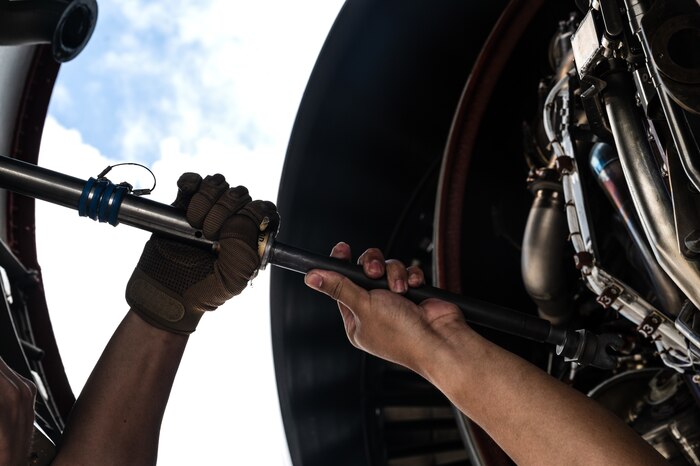 U.S. Air Force Senior Airman Saege Ayala, 22nd Aircraft Maintenance Squadron electrical and environmental technician, closes the cover of a KC-46A Pegasus engine after conducting repairs during the Air Force's Department-Level Exercise series at Andersen Air Force Base, Guam, July 15, 2025. The DLE strengthens and demonstrates the U.S. Air Force’s ability to reach theater at speed and scale, sustain operations, and rapidly pivot to any theater of operation at a moment’s notice while maintaining the strategic initiative. The DLE series encompasses all branches of the Department of Defense, along with allies and partners, employing more than 400 joint and coalition aircraft and more than 12,000 personnel across more than 50 locations across 3,000 miles. (U.S. Air Force photo by Staff Sgt. Tryphena Mayhugh)