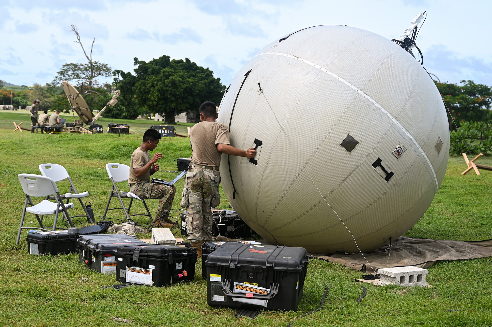 A U.S. Air Force Airman with the 11th Combat Air Base Squadron sets up a ground antenna transmit and receive inflatable satellite to support the 11th Air Task Force in exercise Resolute Force Pacific in Saipan, Northern Mariana Islands, July 14, 2025. The 11 CABS is an elite squadron designed to execute flexible and uncharted mission directives, worldwide. (U.S. Air Force photo by 2nd Lt. Grace Brandt)