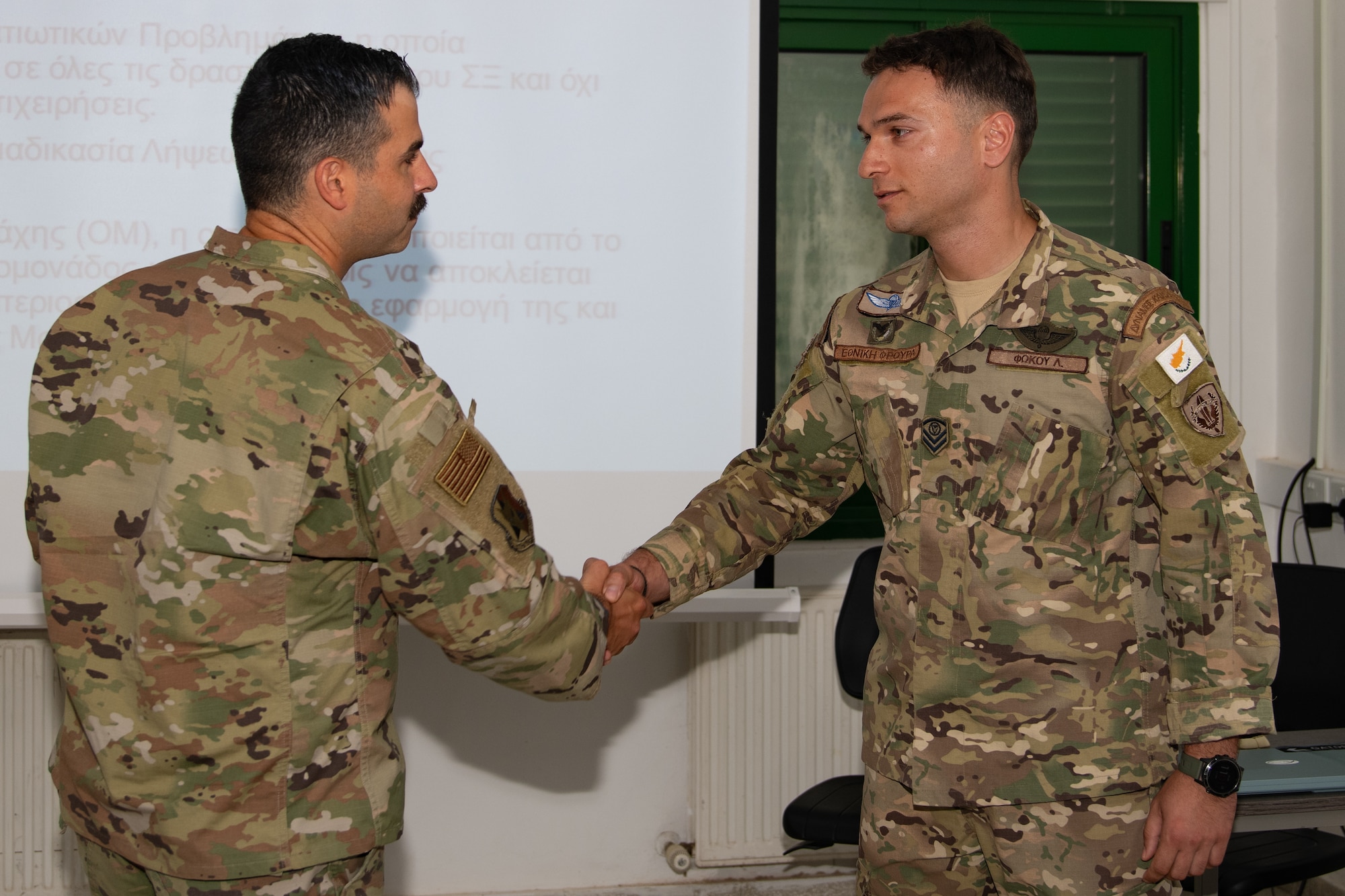 U.S. Air Force Chief Master Sgt. Justin Kelley, 177th Fighter Wing Staff senior enlisted leader, right, presents the “Jersey Devil Chiefs Council” coin to Cyprus Air National Guard Warrant Officer Andreas Christoforou, inaugural Non-commissioned Officer development course lead observer and instructor, for excellence.