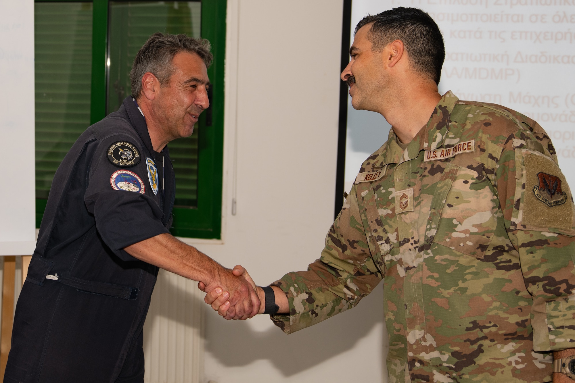 U.S. Air Force Chief Master Sgt. Justin Kelley, 177th Fighter Wing Staff senior enlisted leader, right, presents the “Jersey Devil Chiefs Council” coin to Cyprus Air National Guard Warrant Officer Andreas Christoforou, inaugural Non-commissioned Officer development course lead observer and instructor, for excellence.