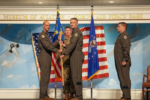 two airmen hold a guidon on stage