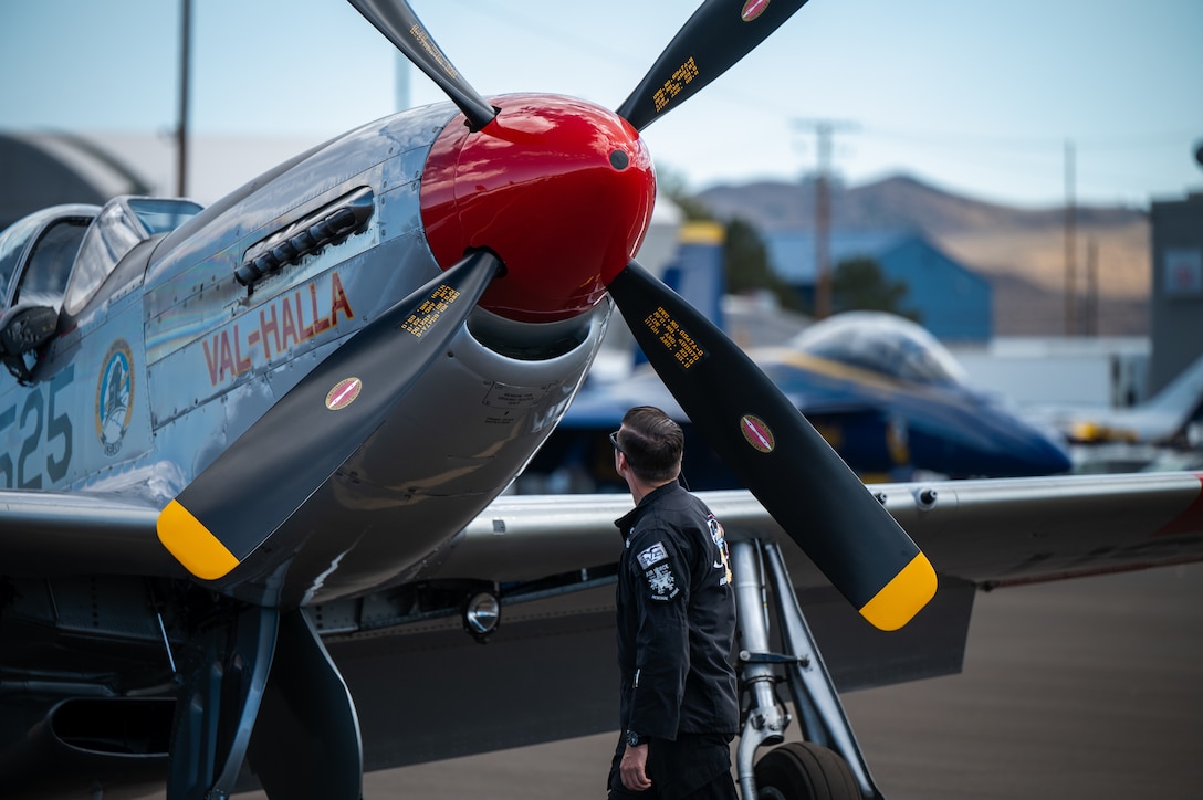 U.S. Air Force Senior Airman Carter Pals, F-16 Viper Demonstration Team dedicated crew chief, walks past a P-51 Mustang belonging to Greg “BA” Anders, Air Force Heritage Flight Foundation (HFF) pilot, prior to the heritage flight formation flight at the Reno Air Show in Reno, Nevada, Oct. 5, 2024. The team travels across the United States to perform at air shows, occasionally paired with an HFF pilot and aircraft to illustrate the technological advancements in aviation the U.S. has produced in 20th and 21st centuries.