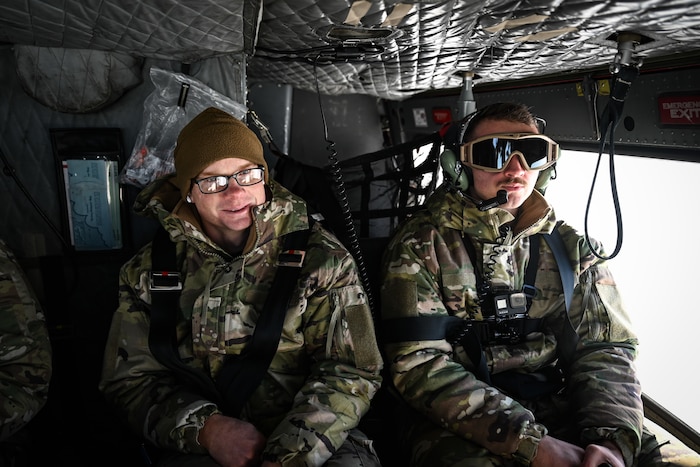 Airmen ride in a helicopter.