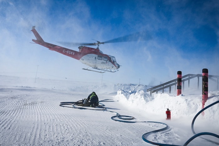 A helicopter flies away from Hall Beach Radar Station.