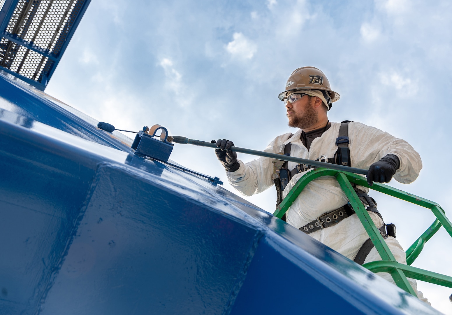 Romeo Aquino, painter, Code 730, Crane Maintenance, works high above the shipyard while repainting Portal Crane 92, July 31, 2025, at Puget Sound Naval Shipyard & Intermediate Maintenance Facility in Bremerton, Washington. A team of painters from Code 730 has spent the better part of the summer updating cranes 80, 82 and 92. The paints used are silicone alkyd enamel, adding a higher gloss sheen for ease of cleaning purposes, for better UV deflection which also helps slow the oxidation process down. (U.S. Navy photo by Wendy Hallmark)