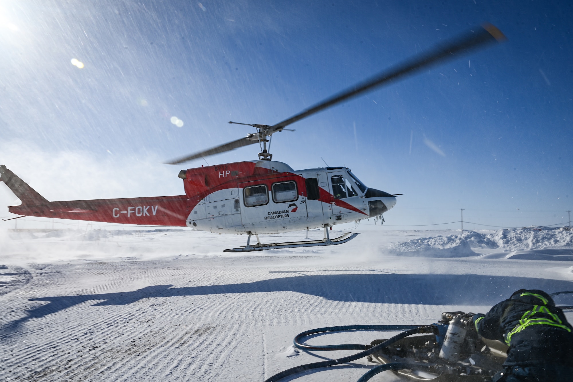 A helicopter lands at Hall Beach Radar Station.