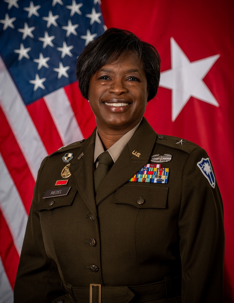 head and shoulder photo of Brig. Gen Riedel with two flags