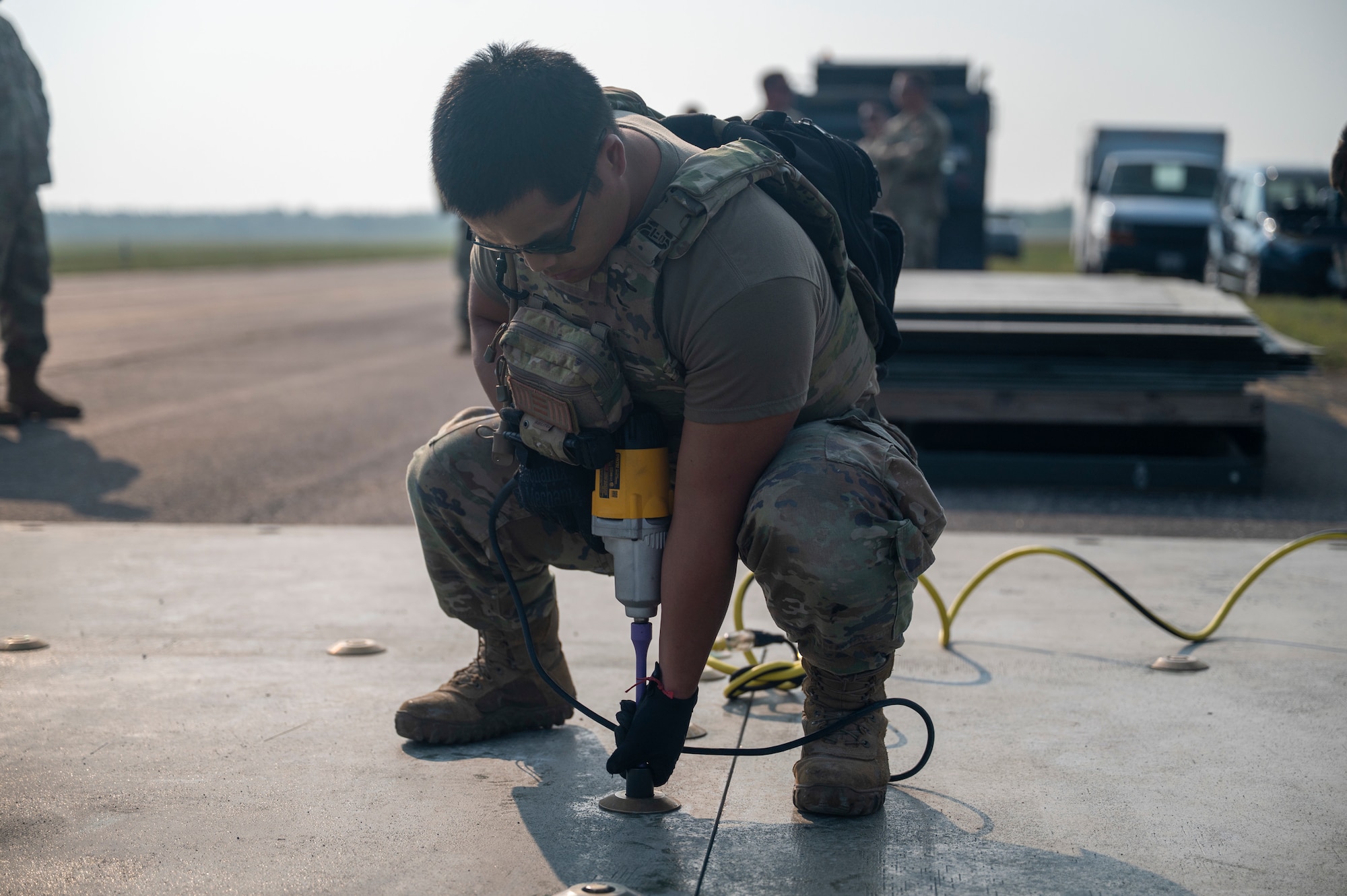 United States Air Force service members perform repairs to an airfield taxiway