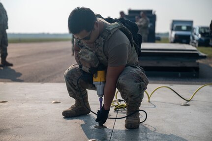 United States Air Force service members perform repairs to an airfield taxiway