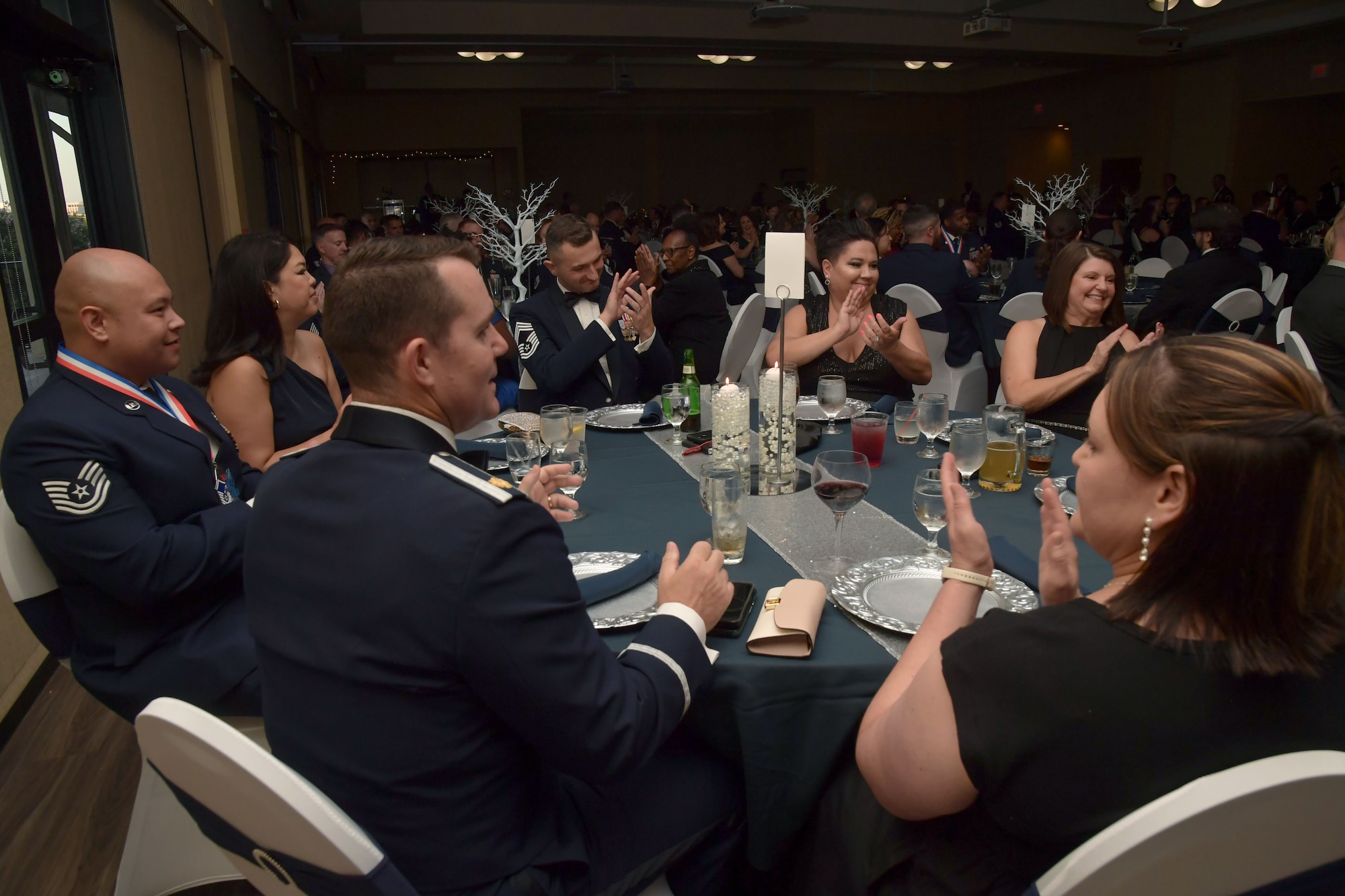 A group of people sit at a dinner table while applauding