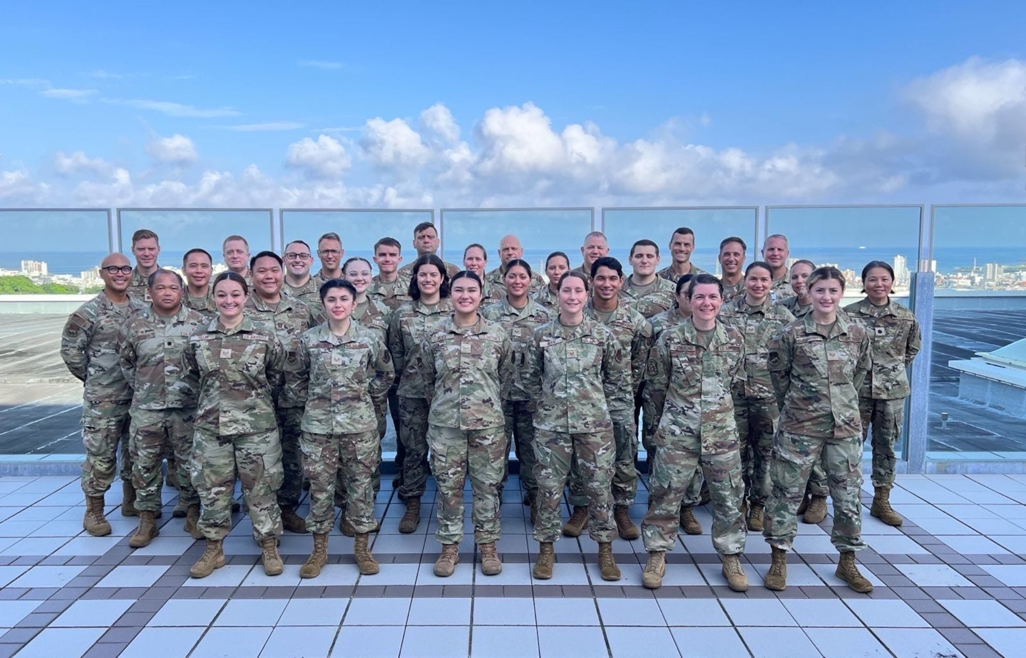 Airmen from the 142nd Medical Group assemble for a group photo atop the U.S. Naval Hospital in Okinawa, Japan, July 17, 2025, during Medical Facility Annual Training (MFAT). The training enhanced joint medical readiness through hands-on clinical experience alongside Navy and Marine Corps personnel. (Courtesy photo)