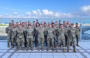 Airmen from the 142nd Medical Group assemble for a group photo atop the U.S. Naval Hospital in Okinawa, Japan, July 17, 2025, during Medical Facility Annual Training (MFAT). The training enhanced joint medical readiness through hands-on clinical experience alongside Navy and Marine Corps personnel. (Courtesy photo)