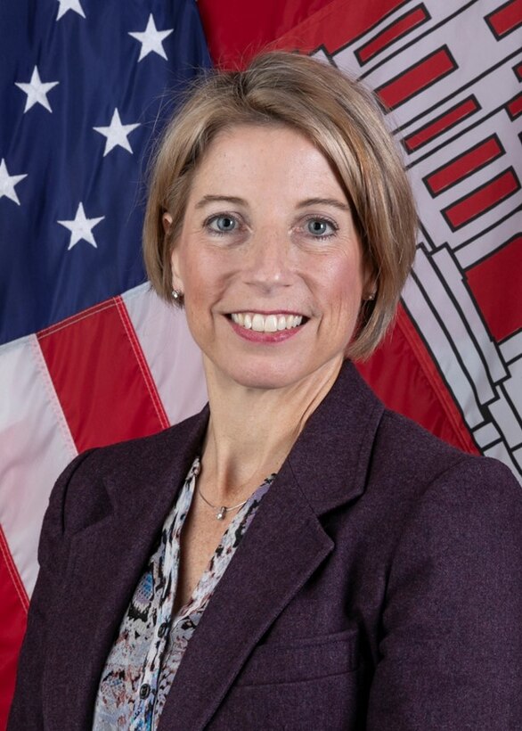 A women poses in front of an American flag and USACE colors.