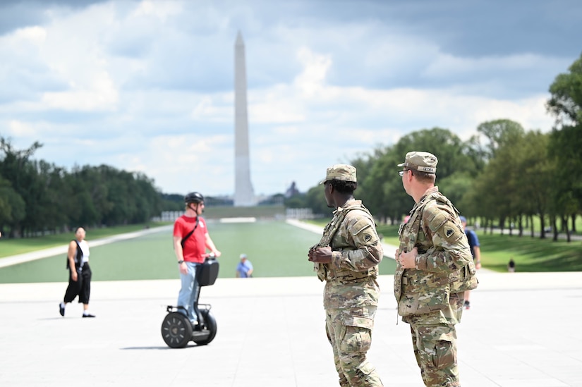 Two guardsmen walk near others on the National Mall.