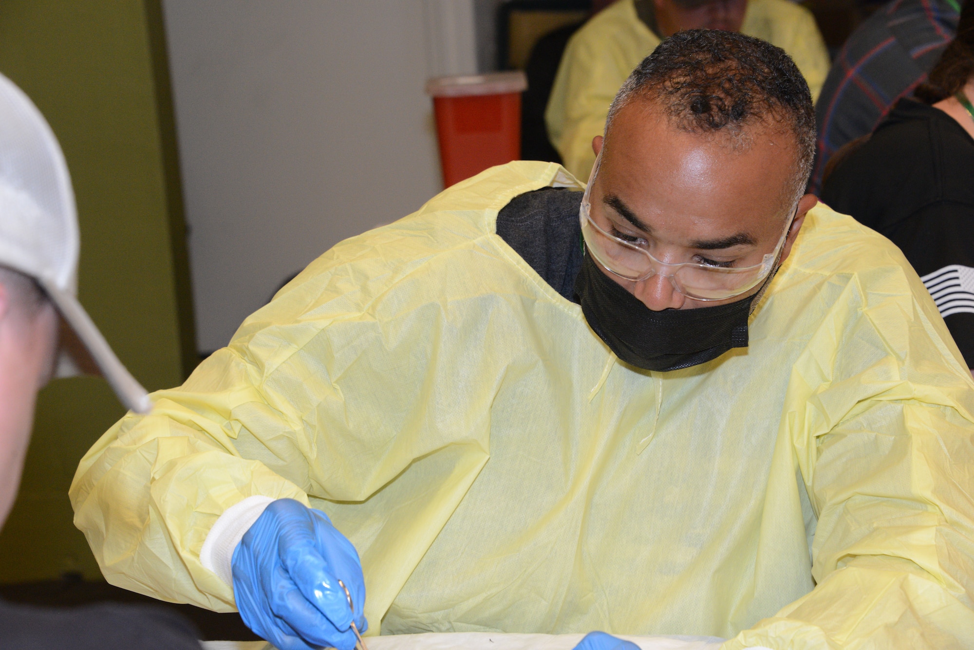 U.S. Air National Guard Tech. Sgt. Jacob Jackson performs sutures on the limb of a postmortem human model that is out of view