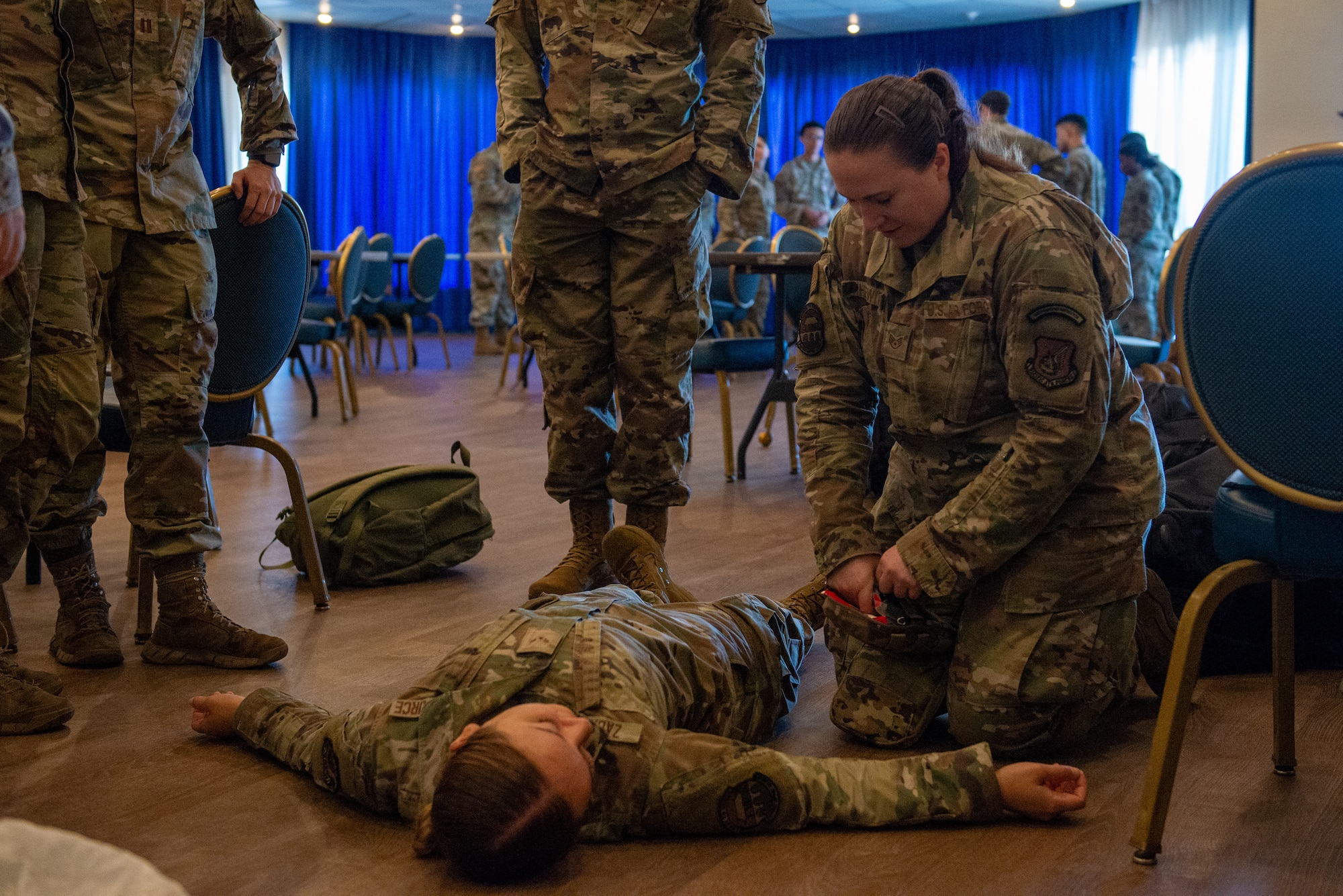 An Airman opens a first aid kit during a casualty training scenario.