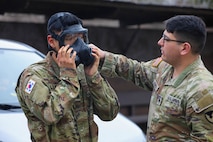 U.S. Army Sgt. Remi Torres, assigned to Headquarters and Headquarters Company, U.S. Army Garrison Yongsan-Casey, helps Korean Augmentation to the U.S. Army Pfc. Hyun Jae Chung don his promask before a gas chamber drill at North Star Range, Uijeongbu, South Korea, March 5, 2025.