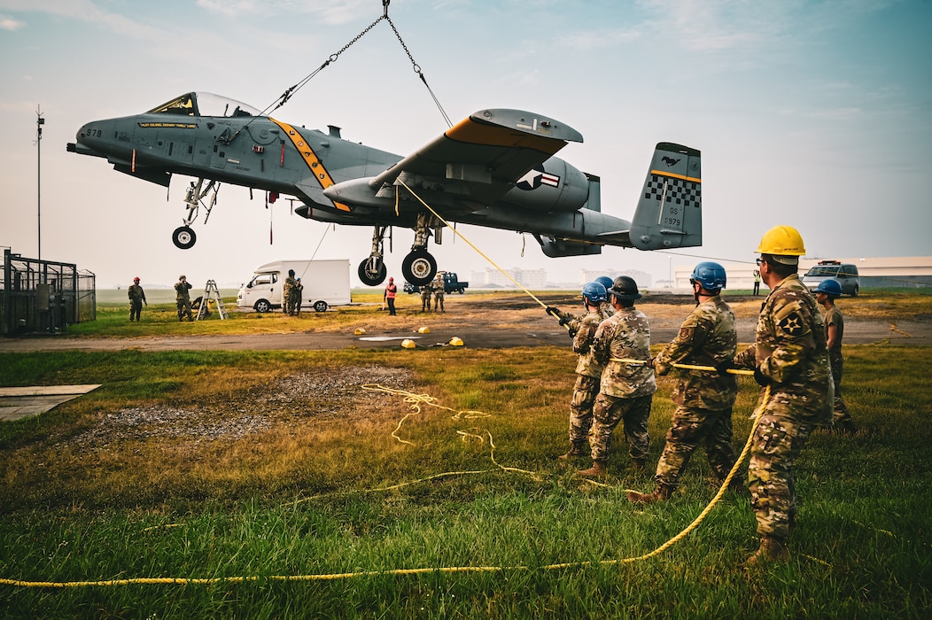U.S. Air Force Airmen from the 25th Fighter Generation Squadron and 51st Maintenance Squadron work together with U.S. Army Soldiers from 2nd Combat Aviation Brigade, 2nd Infantry ROK/U.S. Combined Division and personnel from U.S. Army Garrison Humphreys to lift an A-10 Thunderbolt II aircraft to be put on display on a traffic circle at Camp Humphreys, South Korea, August 2, 2025.