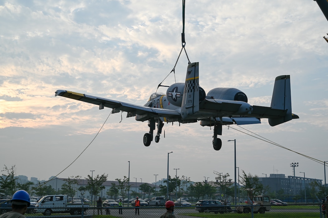 An A-10 Thunderbolt II aircraft gets lifted into position to be escorted down to be put on display at a traffic circle on Camp Humphreys, South Korea, August 2, 2025.